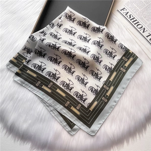 Detail of silk scarf with horse carriage pattern on white plush background with a gift box