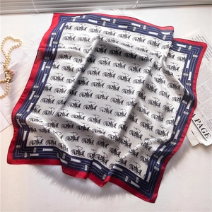 Detail of luxury silk scarf with carriage print on soft plush background with pearls