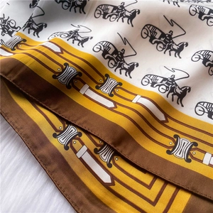 Detail of luxury silk scarf showing horse carriage pattern and gold chain link details