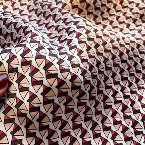 Detailed view of geometric print silk-like fabric with pink and brown triangular patterns