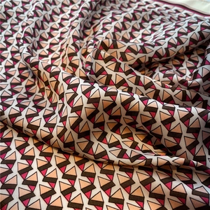 Detail of silk-like scarf featuring pink and brown geometric triangle patterns with fine texture
