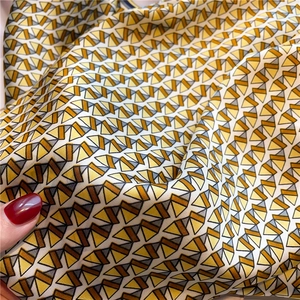 Close-up of geometric triangle pattern silk scarf showing soft texture and glossy finish