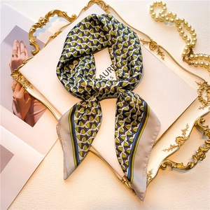 Detailed shot of a geometric silk scarf tied in a bow on a vintage gold relief tray