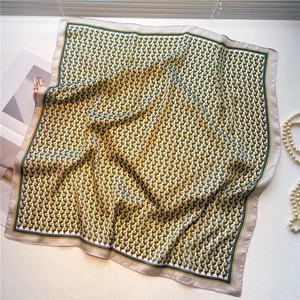 Detail view of geometric silk scarf with green and blue diamond pattern and grey border