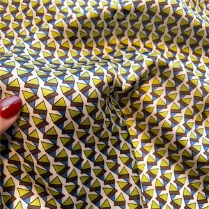 Detailed view of silky fabric with geometric triangle patterns in blue and yellow