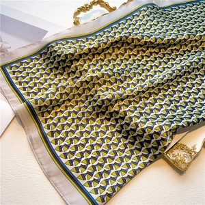 Close-up of geometric silk scarf with blue and green stripes on white background