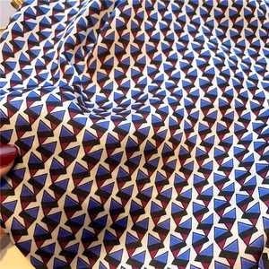 Detail of silk-like fabric showing geometric blue and red triangle pattern and glossy texture