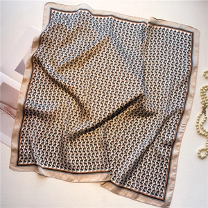 Detailed flat lay of geometric square silk scarf with pearl jewelry on white surface