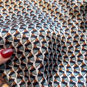 Detail shot of a geometric silk-like scarf showing soft texture and multicolored patterns