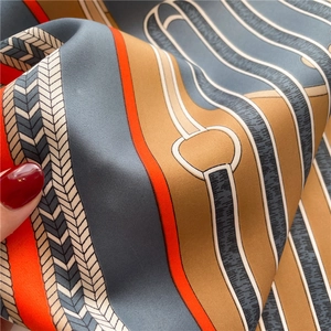 Close-up of silk scarf fabric showing equestrian pattern and smooth texture