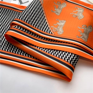 Vue détaillée d'un foulard en soie orange avec motifs zigzag et imprimés équestres