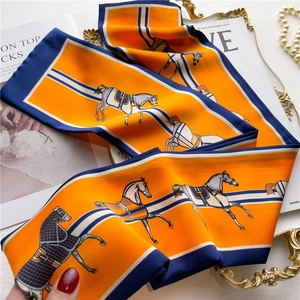 Détail d'un foulard en soie orange avec bordure bleue et motifs de chevaux classiques