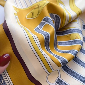 Detail of yellow silk scarf featuring horse head prints and elegant satin texture
