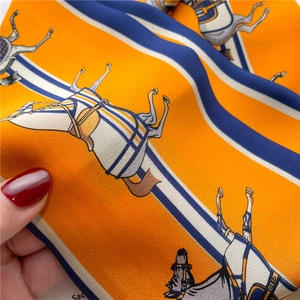 Détail d'un foulard en soie orange avec motif équestre et texture satinée élégante