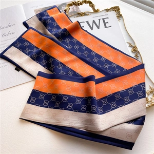Vue détaillée d'un foulard en soie rayé aux motifs de chaînes orange, bleu marine et crème
