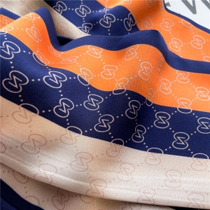 Détail d'un foulard en soie montrant des motifs ondulés et une texture orange