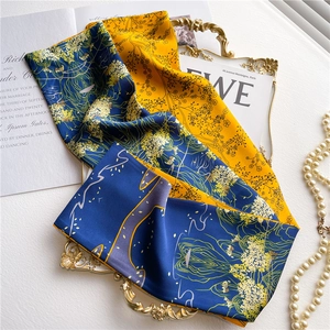Detailed macro of long silk-feel floral scarves stacked elegantly on a vintage gold tray