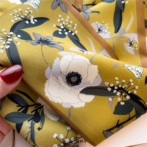 Detailed macro view of mustard yellow silk scarf with elegant floral and butterfly patterns