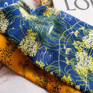 Detail of silk-like satin scarf showing blue abstract patterns and yellow floral textures