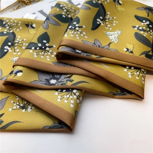 Detailed macro view of mustard yellow floral silk scarf with bee print and rolled edges