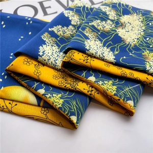 Detail of silk-like floral scarf with navy and yellow contrast and smooth satin texture