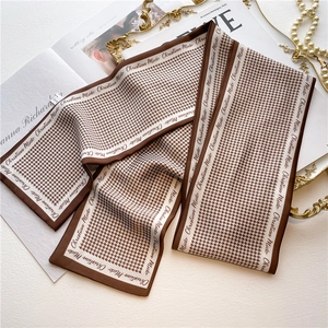 Detail of silk scarf with houndstooth pattern and 100% silk label on a tray