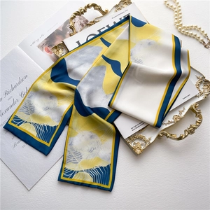 Abstract geometric patterned satin silk scarf in yellow and blue on a luxury tray