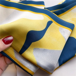 Detail of satin scarf featuring geometric blocks in blue and yellow with smooth texture