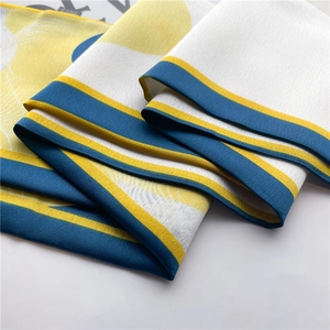 Detailed view of artistic silk scarf with yellow and blue circular print and fine stitching