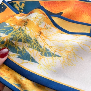 Detailed close-up of glossy silk scarf texture with vibrant tree pattern and blue hem