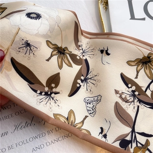 Close-up of floral silk scarf with butterfly print and elegant dark brown edges
