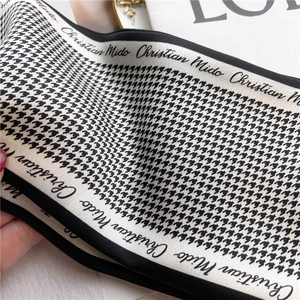 Detail of elegant houndstooth silk scarf with script lettering and luxury texture