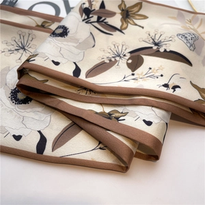 Detailed close-up showing elegant floral and insect prints on high-quality silk scarf fabric