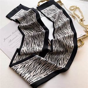Detailed view of long zebra print silk scarf with brand text on elegant white background