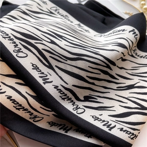 Macro shot of zebra pattern silk scarf texture with Christian Mido lettering and pearls
