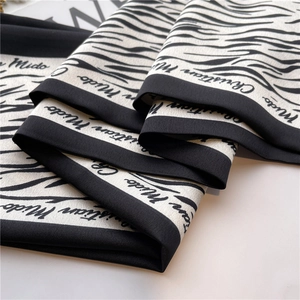 Detailed view of the black and white animal print silk scarf with luxury script lettering
