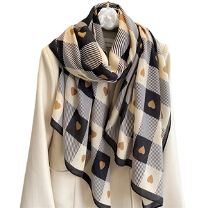 Checkerboard pattern scarf with heart motifs draped over a white blazer on a hanger