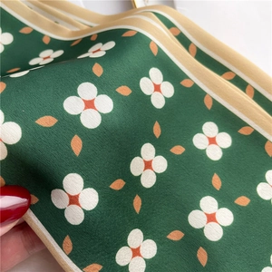 Close-up of floral pattern on dark green silk scarf with high-quality satin texture