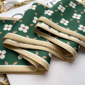 Close-up of silk-like dark green scarf featuring floral patterns and soft satin texture