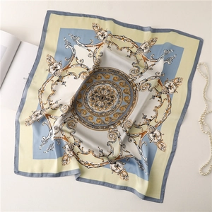 Close-up of silk scarf with baroque patterns next to pearls and a fashion magazine