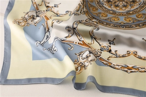 Detailed macro view of baroque print silk scarf with golden patterns and soft satin folds