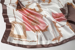 Detailed close-up of Baroque silk scarf texture with gold chain and key pattern