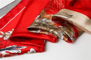 Macro detail of red satin silk scarf showing intricate peony floral patterns and glossy texture