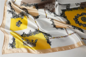 Detail of silk satin scarf featuring baroque patterns with gold crowns and chain prints