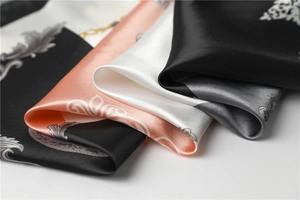 Close-up of luxury satin silk scarf featuring baroque patterns and golden chain details