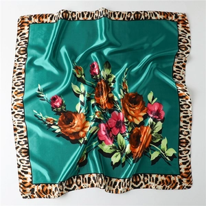 Detailed close-up of emerald green silk scarf featuring red roses and leopard print borders