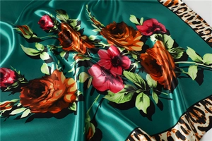 Macro view of silky satin scarf featuring red roses and leopard print borders