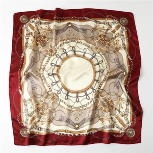 Detailed macro view of satin square scarf with burgundy border and gold chain patterns