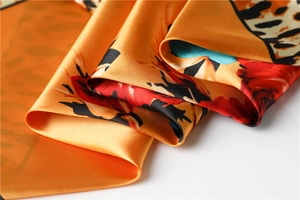 Macro shot of satin leopard and floral print scarf with vibrant orange silk texture
