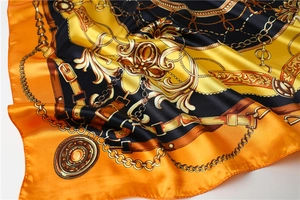 Macro detail of satin scarf showing golden chain baroque patterns and glossy texture